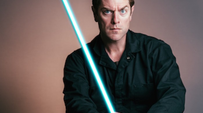 Artist Charles Ross holding blue lightsaber.